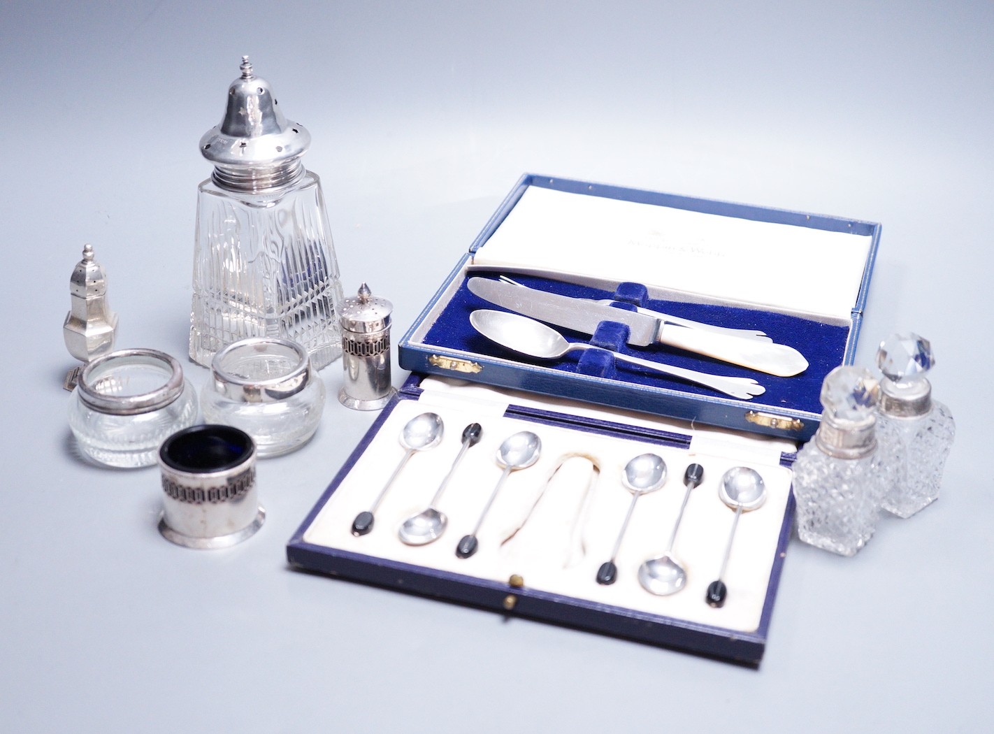 A modern 17th century style silver dog nose christening spoon and fork by Mappin & Webb, an associated knife, a cased set of six silver bean end coffee spoons (lacking tongs), a silver three piece condiment set and five